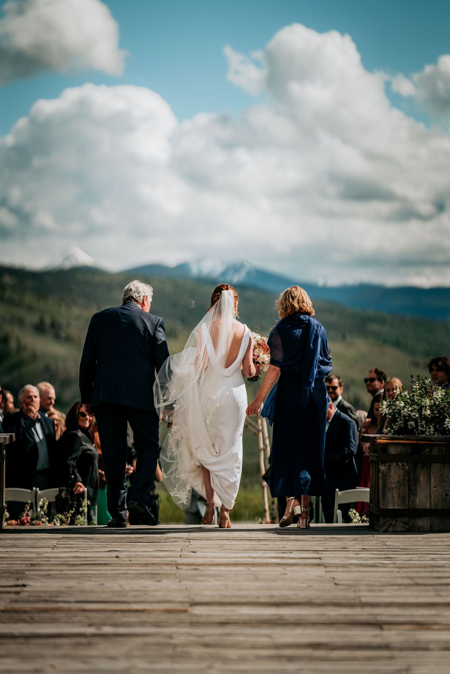 Wedding ceremony on mountain deck with dramatic cloudy sky backdrop.