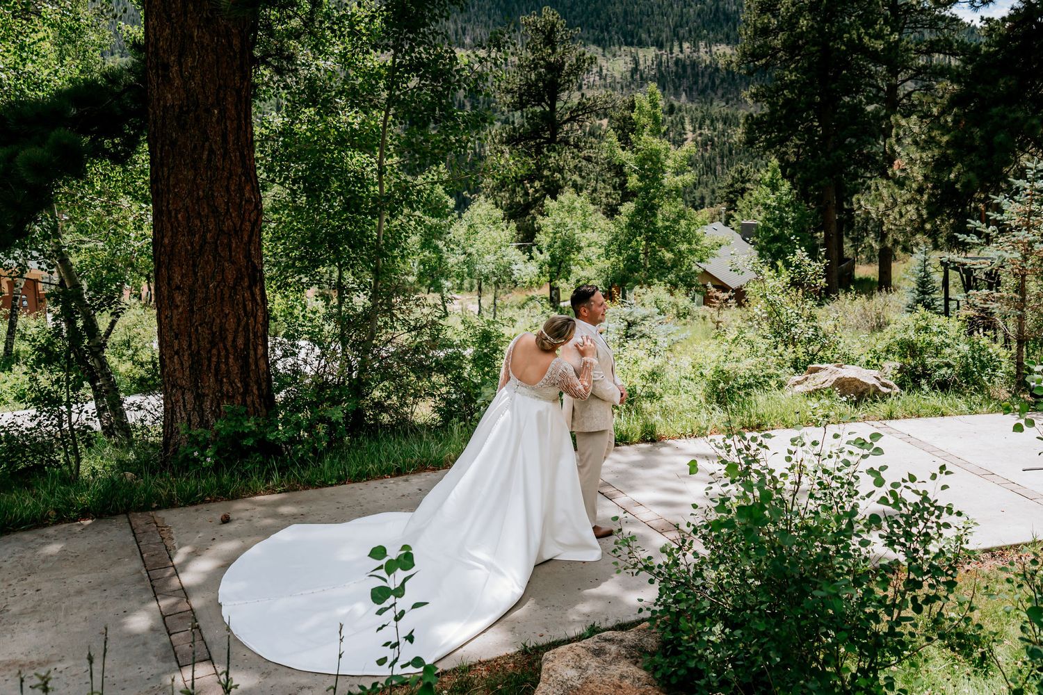 Elegant outdoor wedding moment on stone pathway surrounded by pine trees.