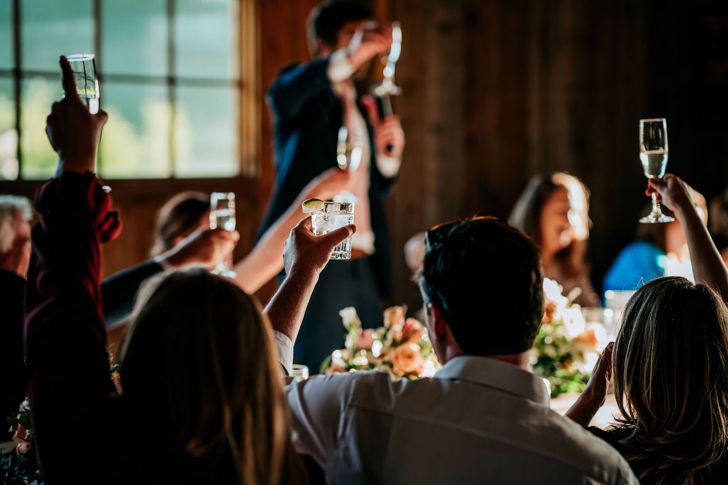 Wedding guests raise champagne glasses for a toast during reception dinner.
