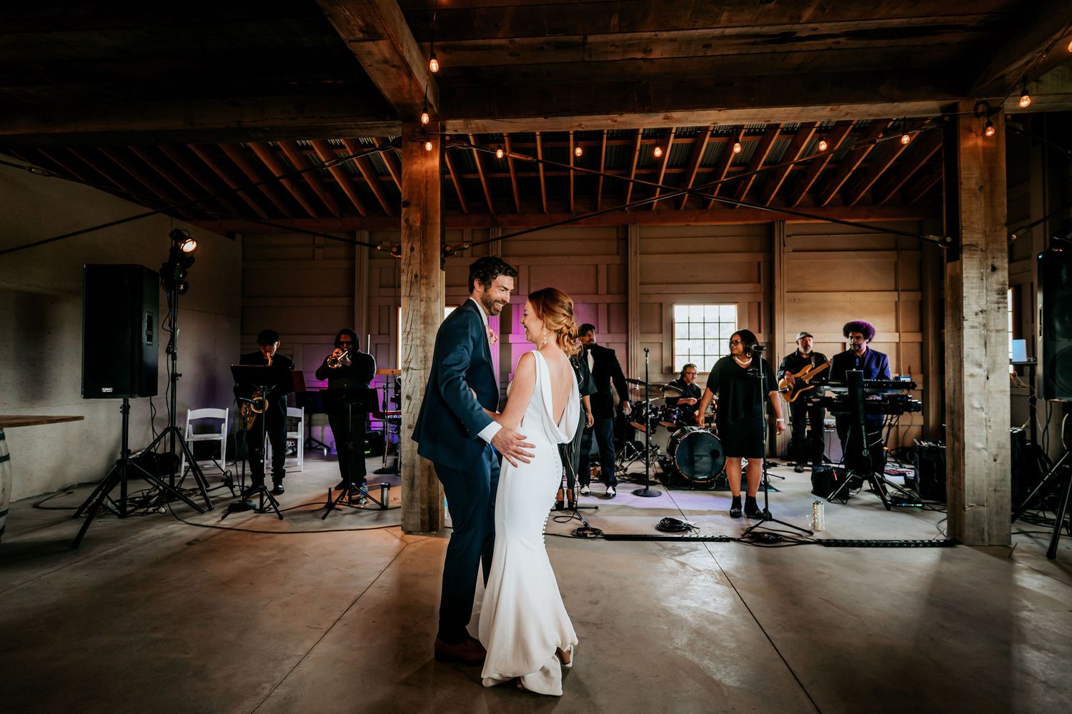Couple dancing at their wedding reception with a live band performing in the background.