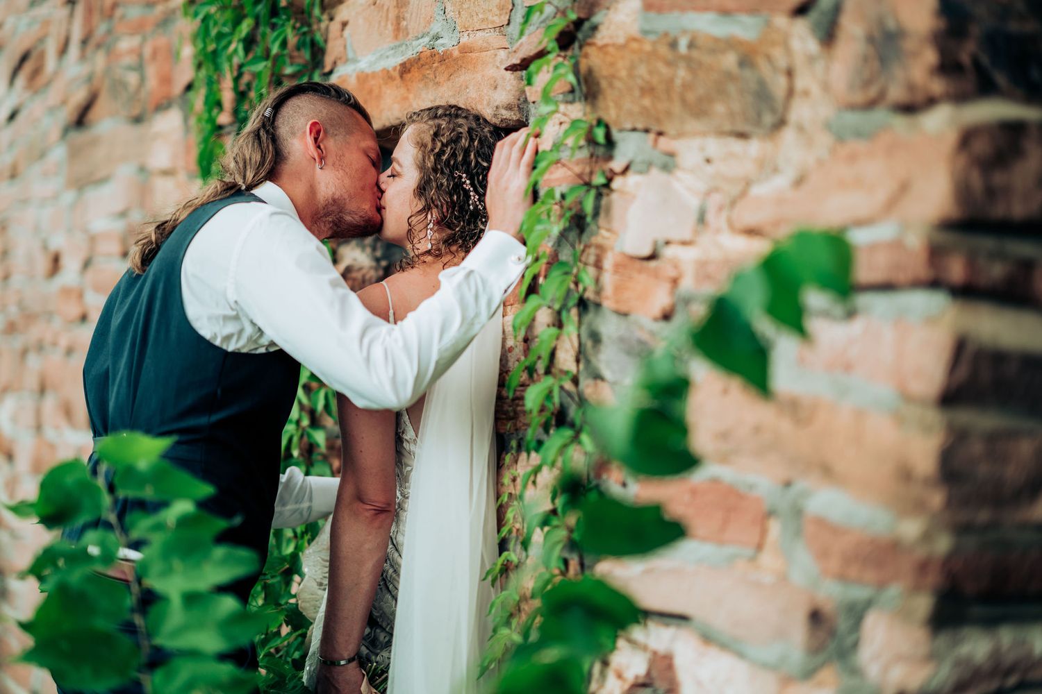 An intimate wedding portrait moment shared against a rustic brick and ivy backdrop.