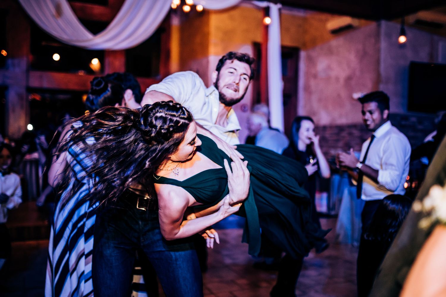 Dynamic dance partners perform an acrobatic lift move during a lively dance party.