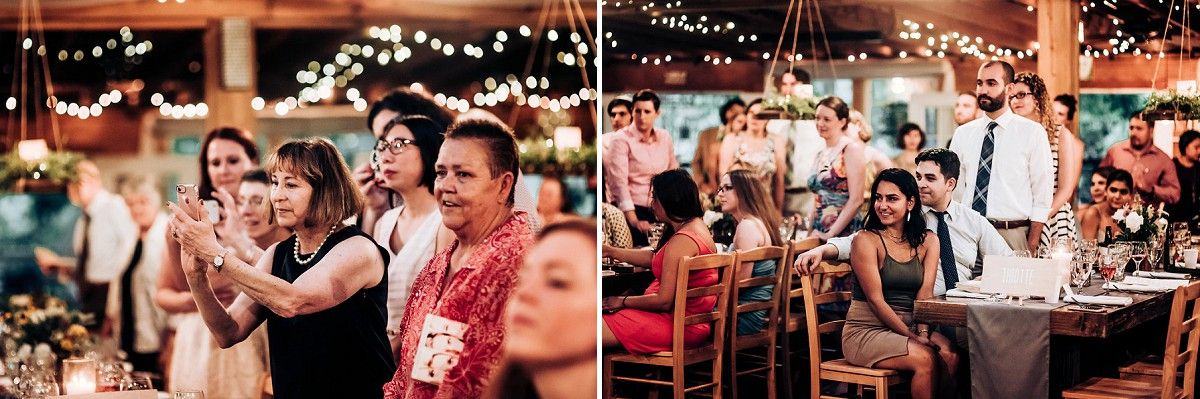 Wedding guests watching and celebrating during a reception filled with string lights.
