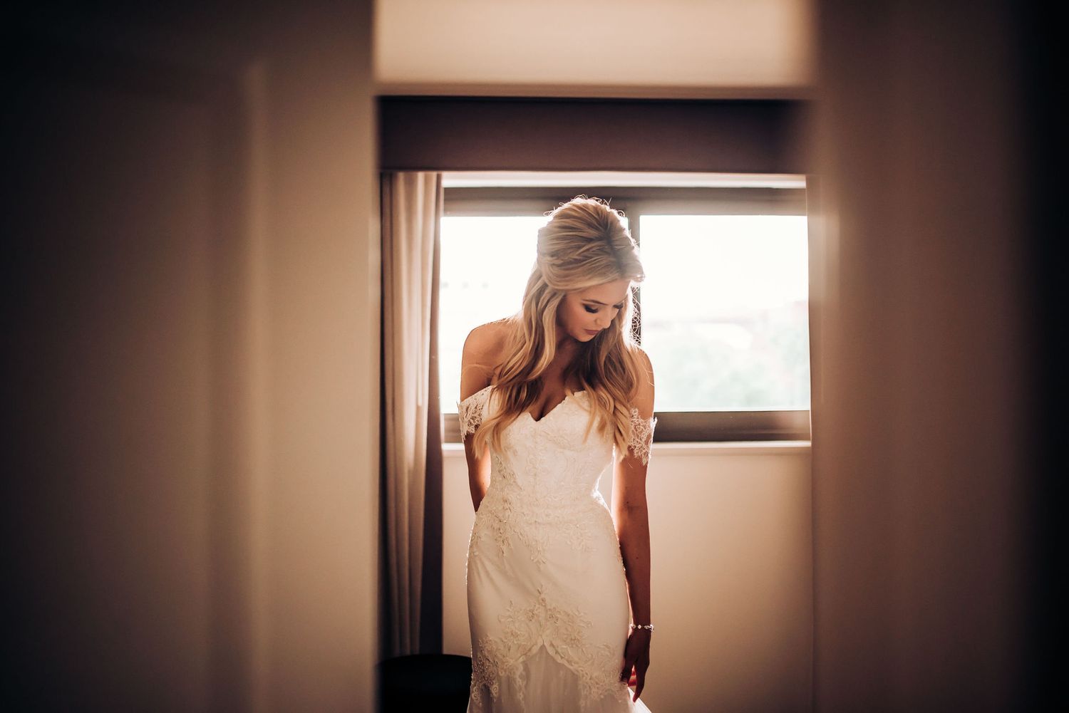 Silhouette of a wedding dress near a window creating a soft, ethereal bridal moment.