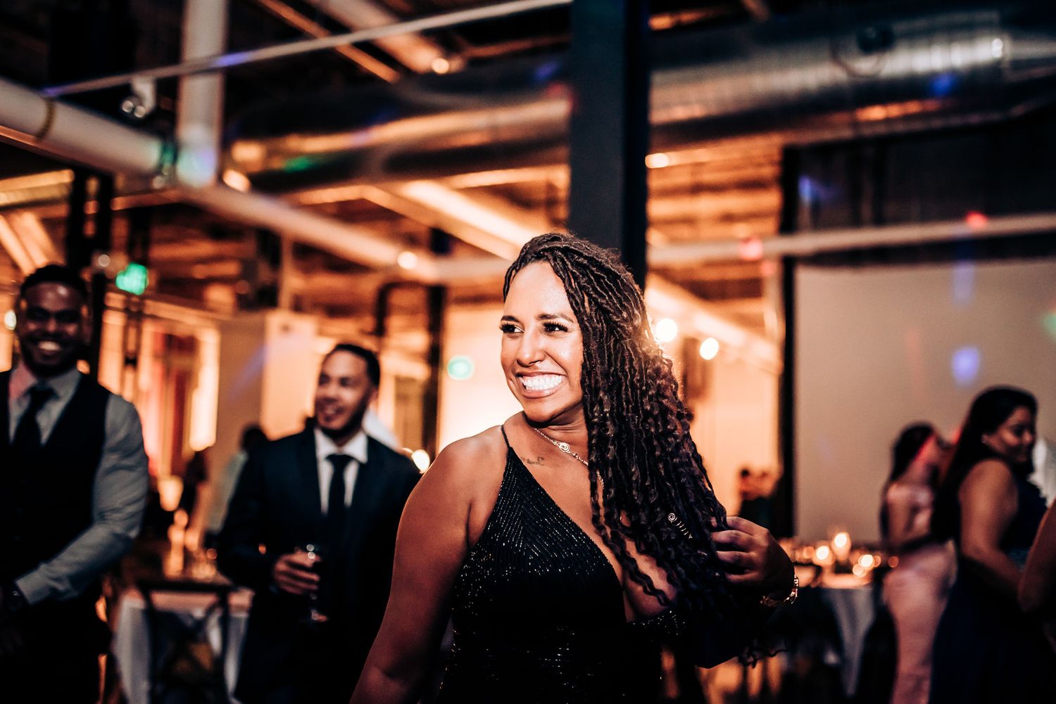 A guest smiles while enjoying the festivities at an industrial-style wedding venue.