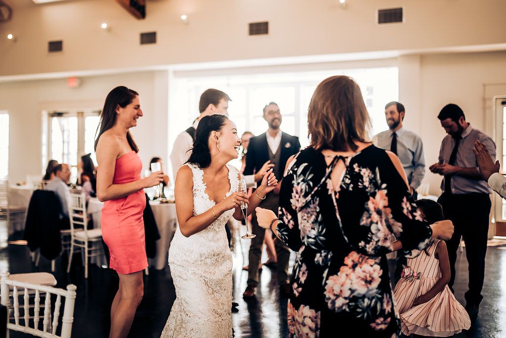 Wedding celebration with guests dancing and mingling in elegant indoor venue.