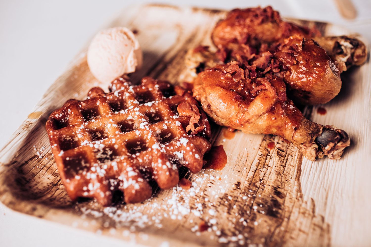 Artisanal waffles and pastries dusted with powdered sugar on wooden surface.