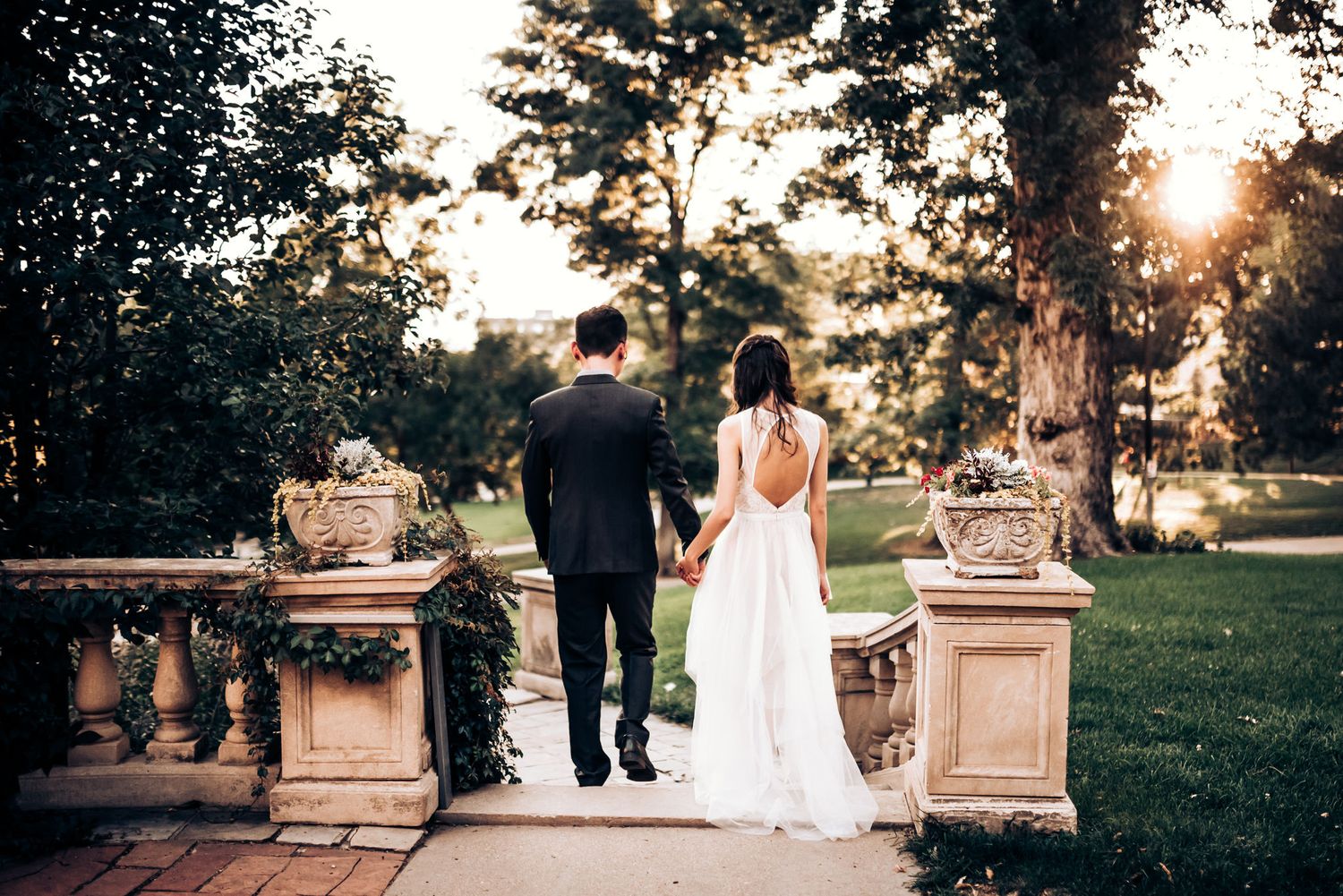 Couple walks away along stone path during sunset after their wedding ceremony.
