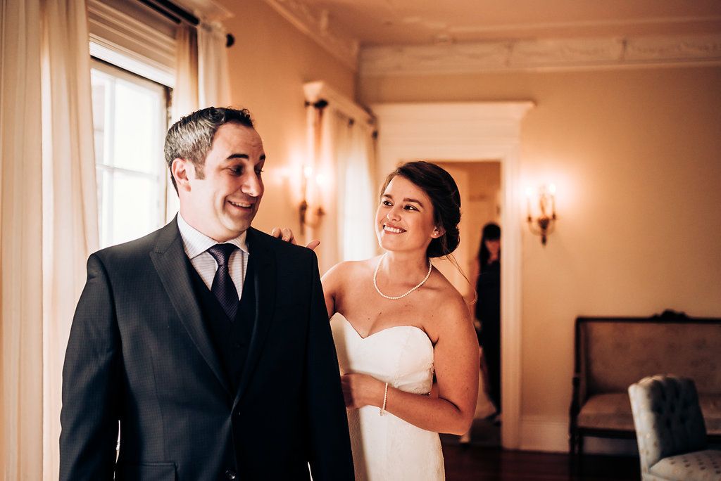 A joyful wedding couple shares a laugh during their first look.