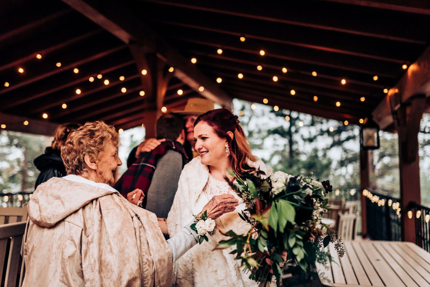 Wedding celebration on covered porch decorated with string lights and rustic ambiance.
