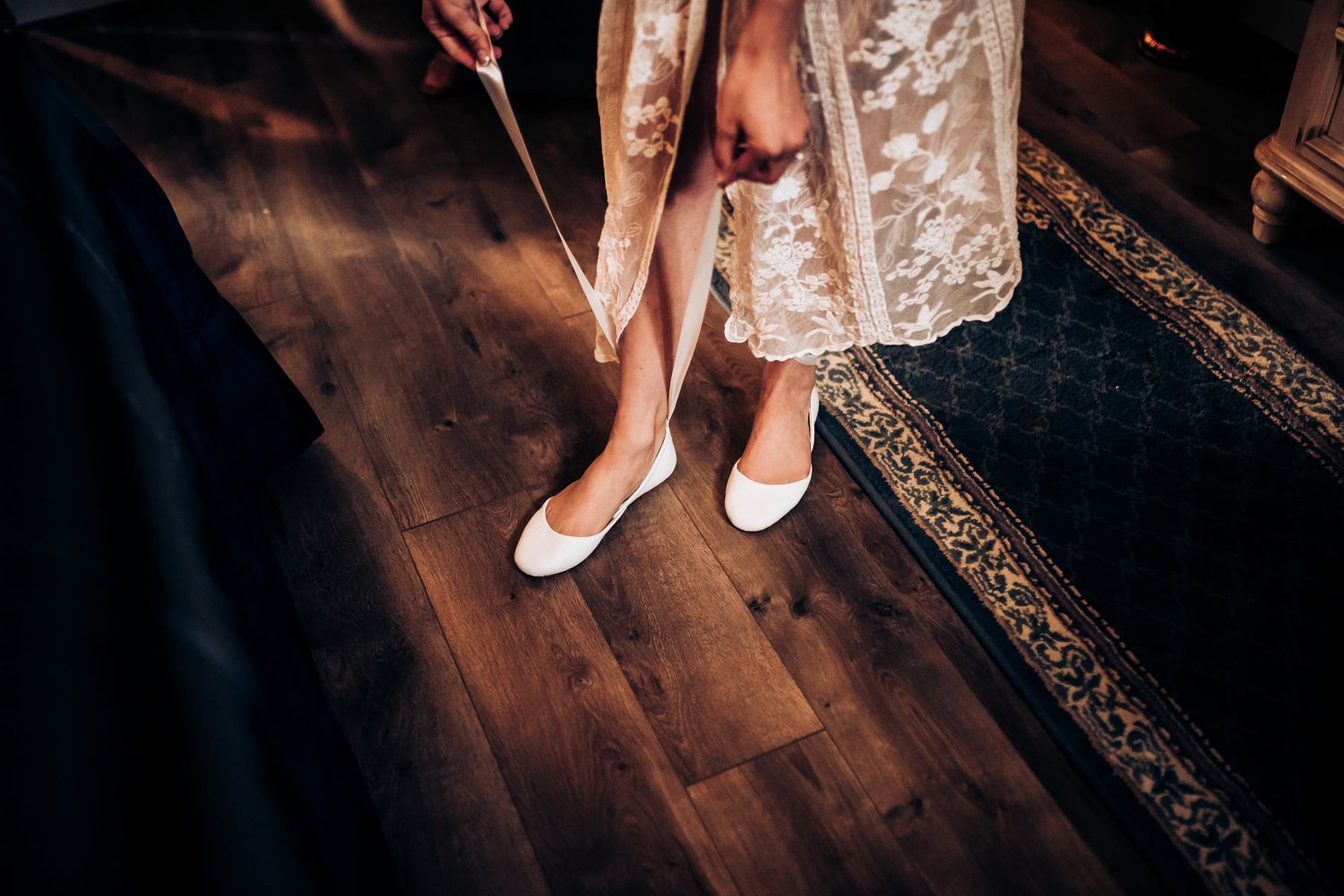 White bridal shoes being put on against hardwood floor.