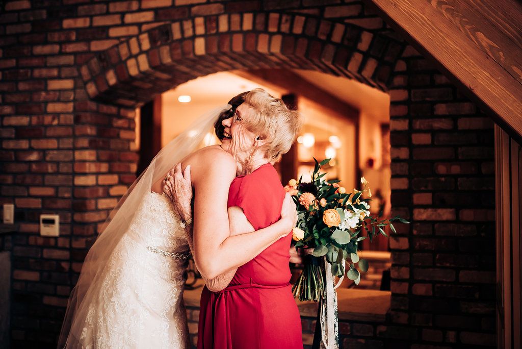 An emotional embrace captured in warm lighting under a brick archway with floral bouquet.