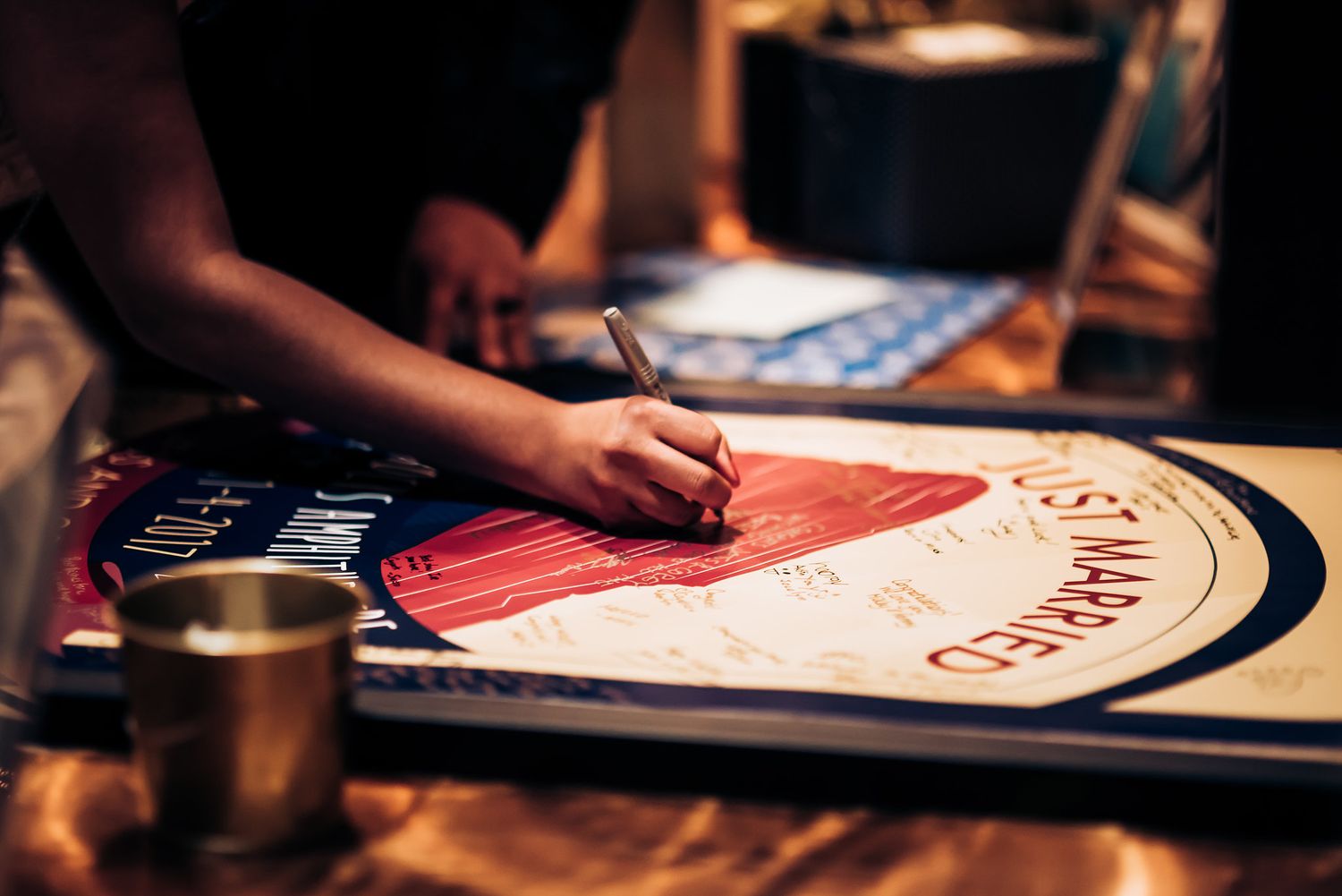 Close-up shot of hands signing a guest book at a wedding reception.