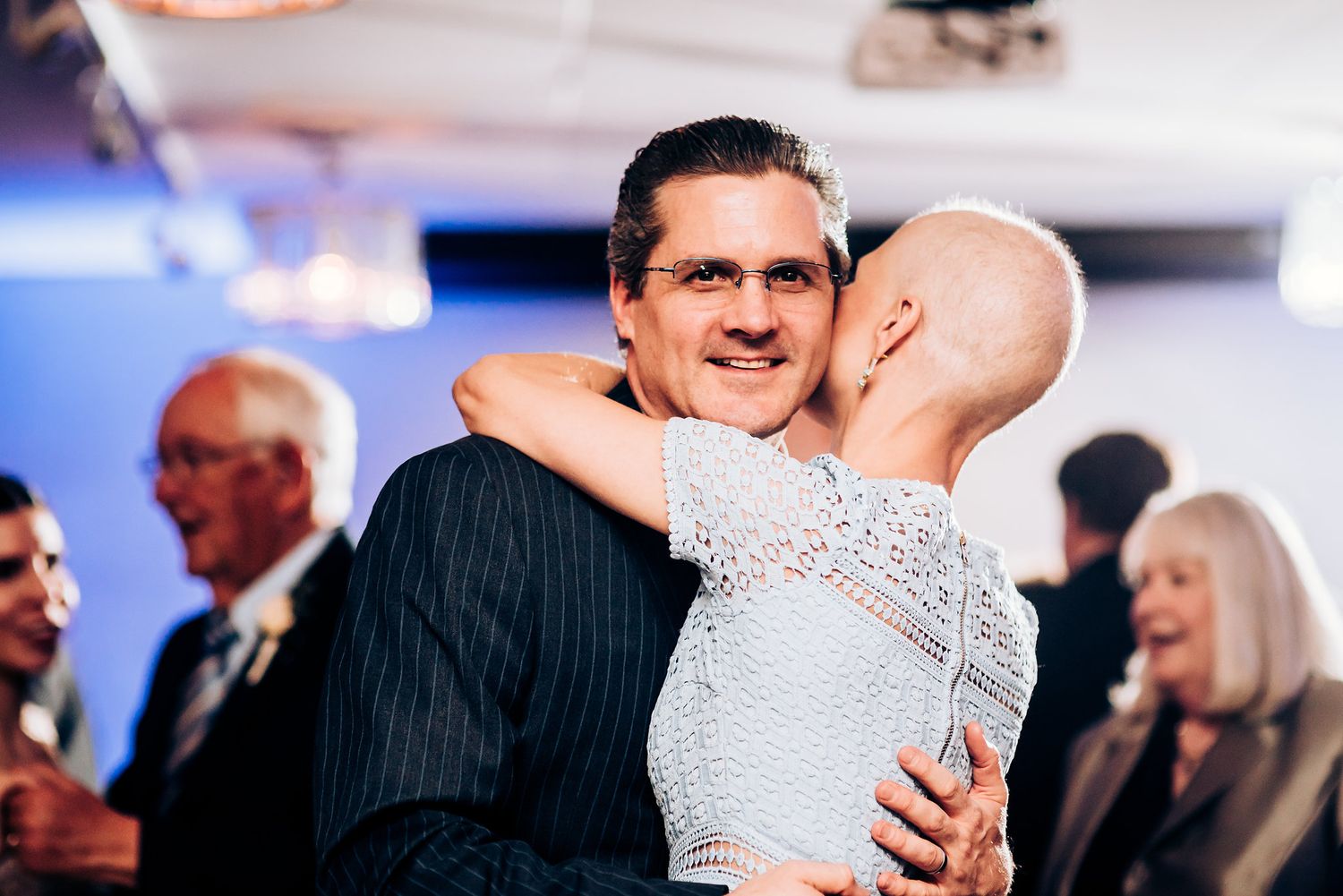 Two people share a tender moment during a dance at a formal event.