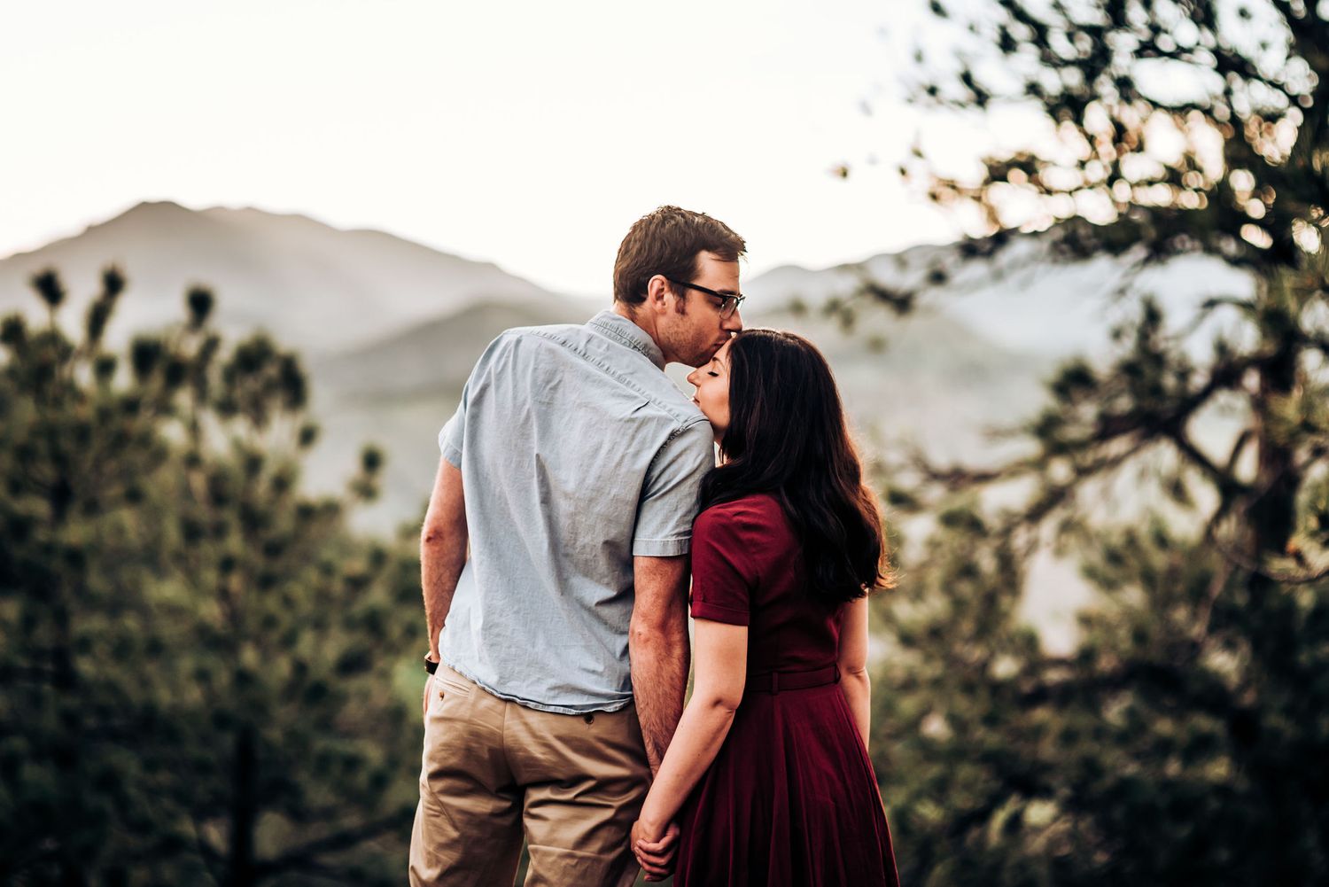 A romantic couple shares an intimate moment against a backdrop of mountain peaks.