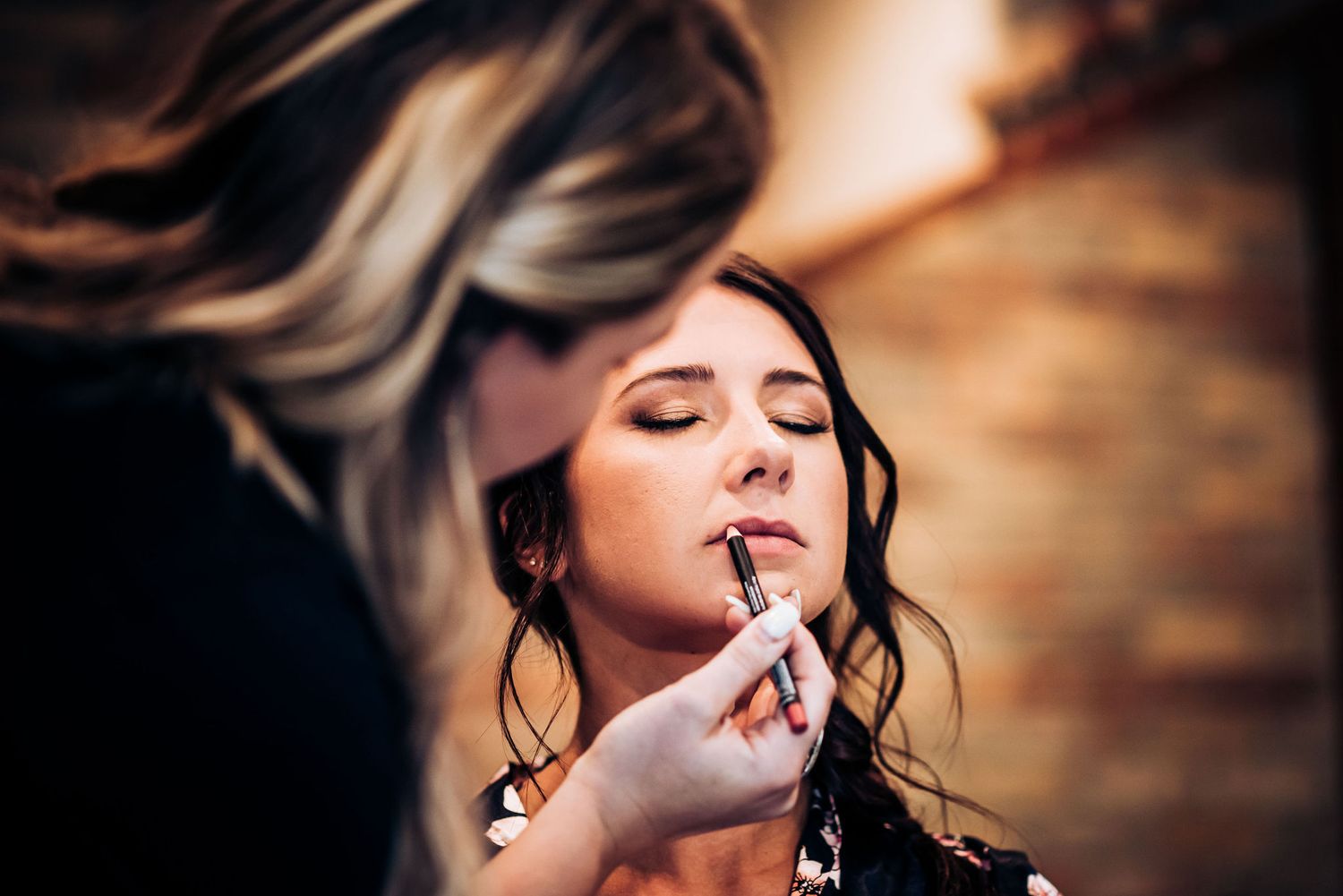 A makeup artist applying lipstick during bridal preparations.