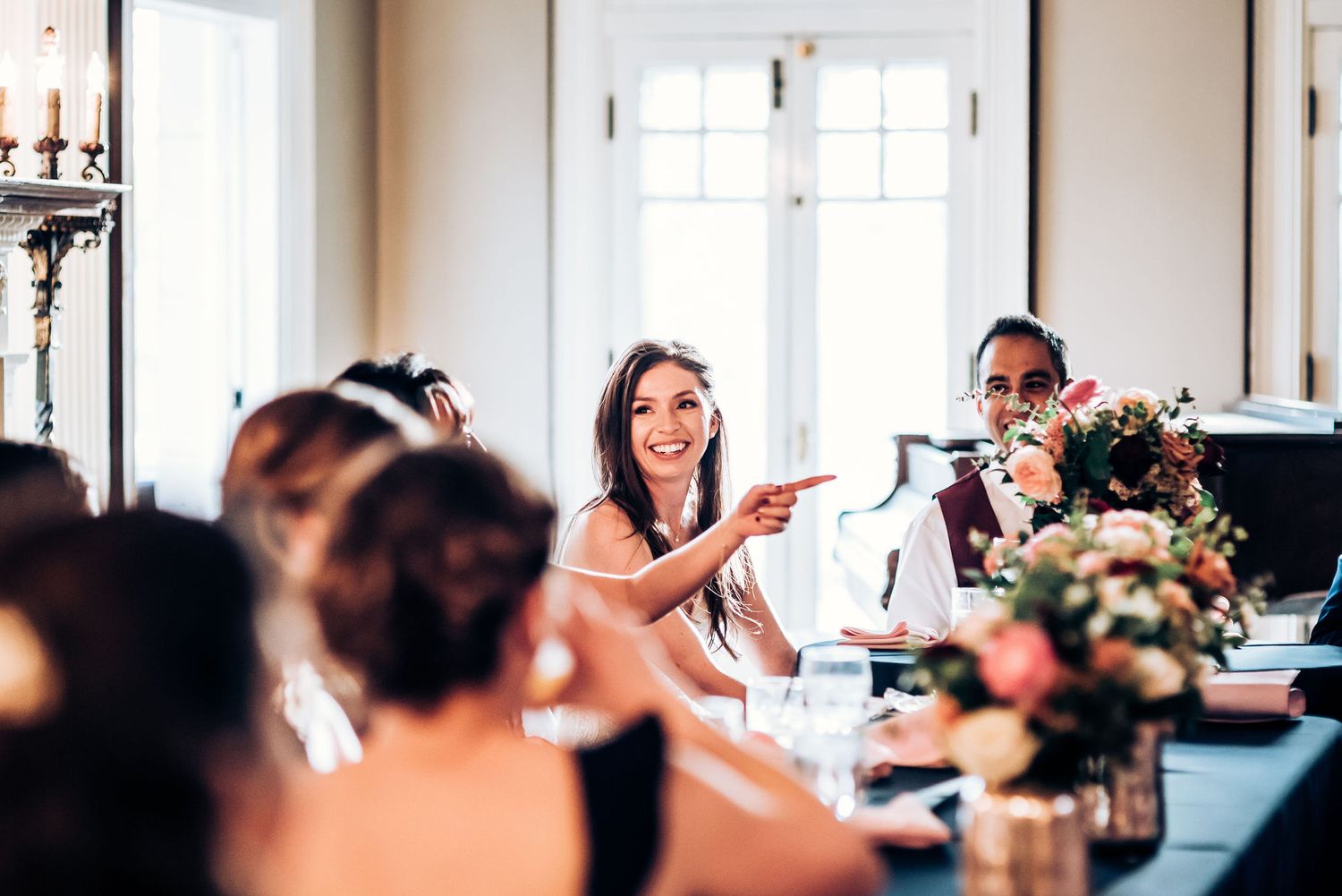 Wedding reception guests socializing around an elegant dining table with floral centerpieces.