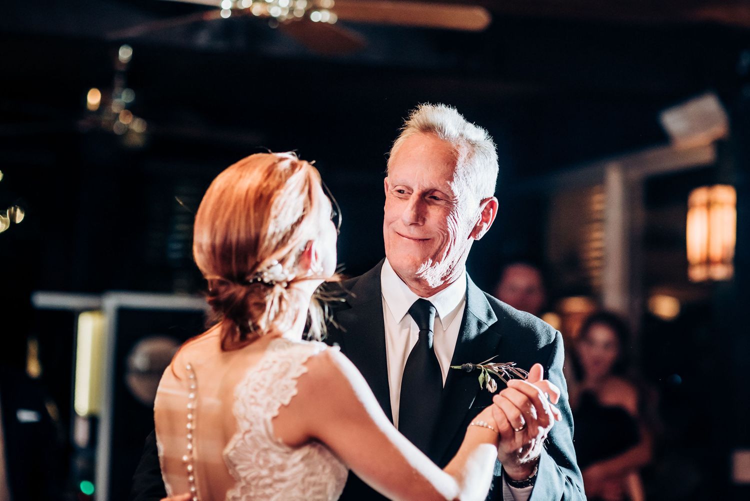 A couple shares an elegant dance moment at their wedding reception with warm lighting.