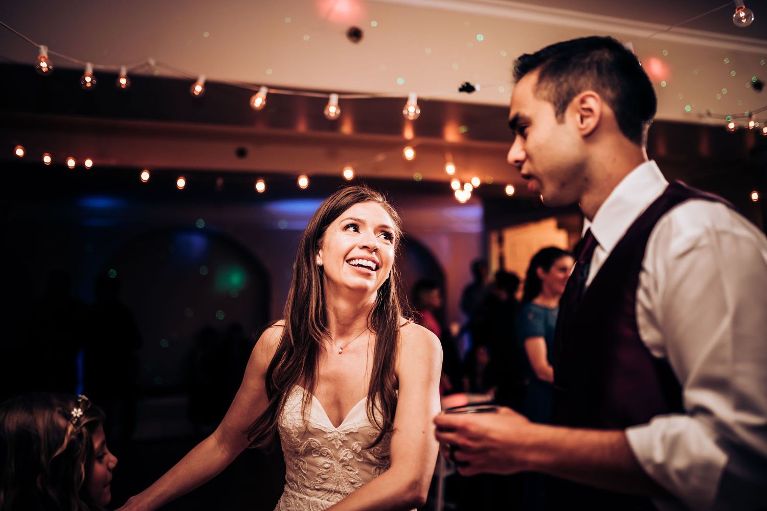 Guests enjoying conversation and laughter under string lights at an evening celebration.