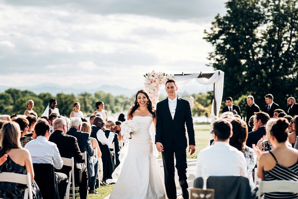 Joyful wedding recessional with guests seated outdoors under cloudy skies.