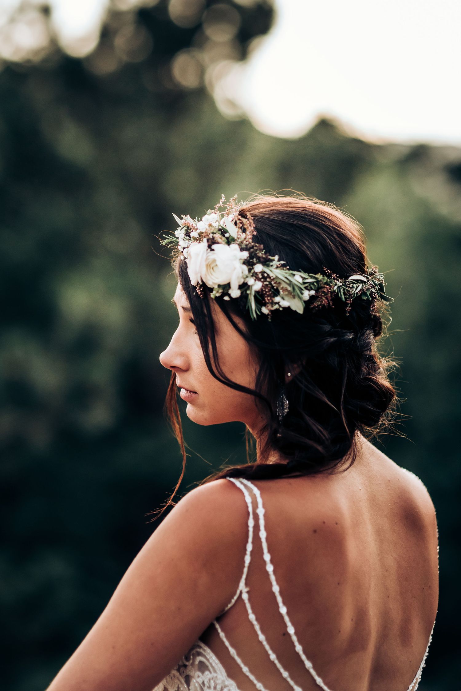 Back view of bride wearing delicate floral crown and strappy open-back wedding dress.
