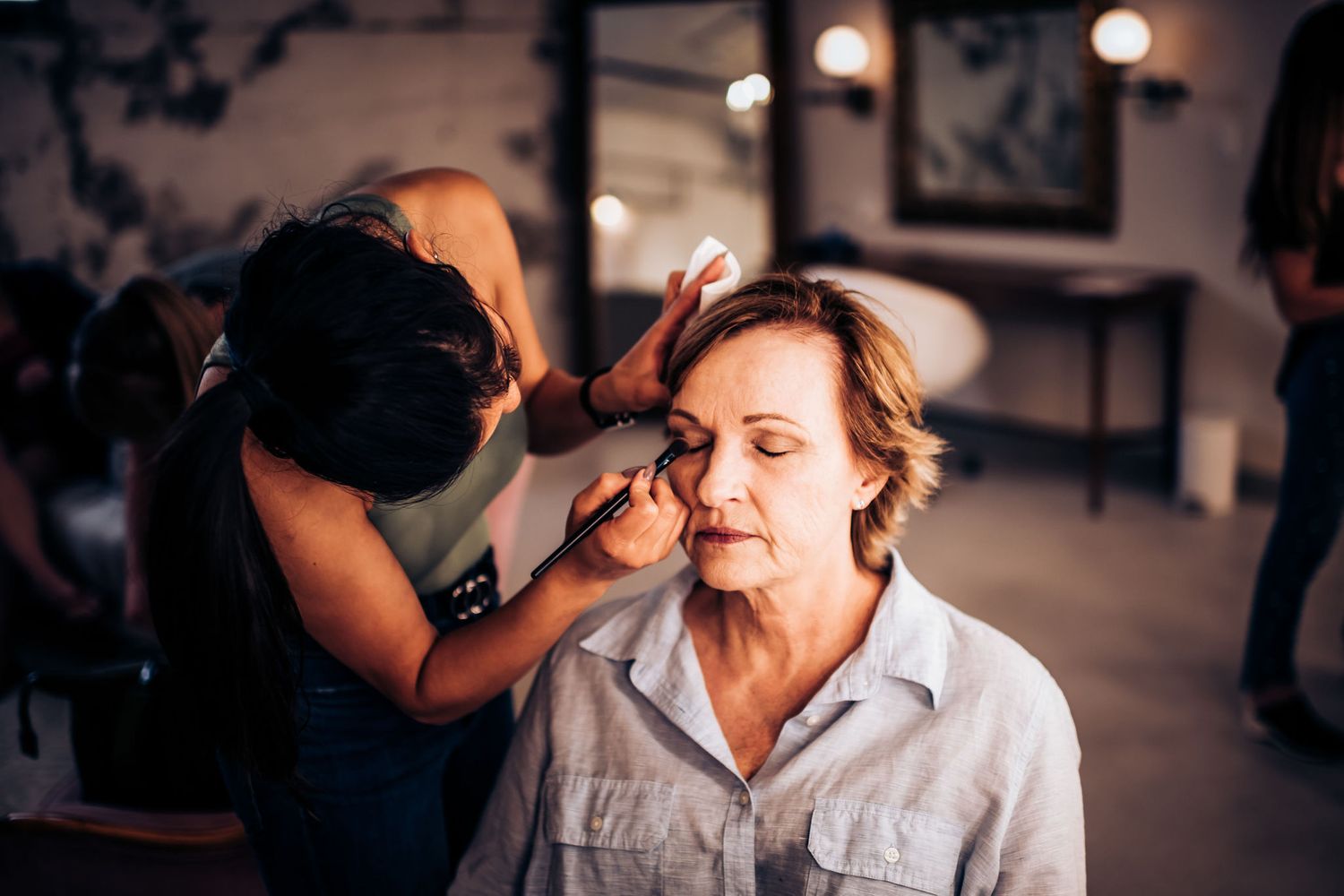 Professional makeup application in progress at a well-lit beauty salon.