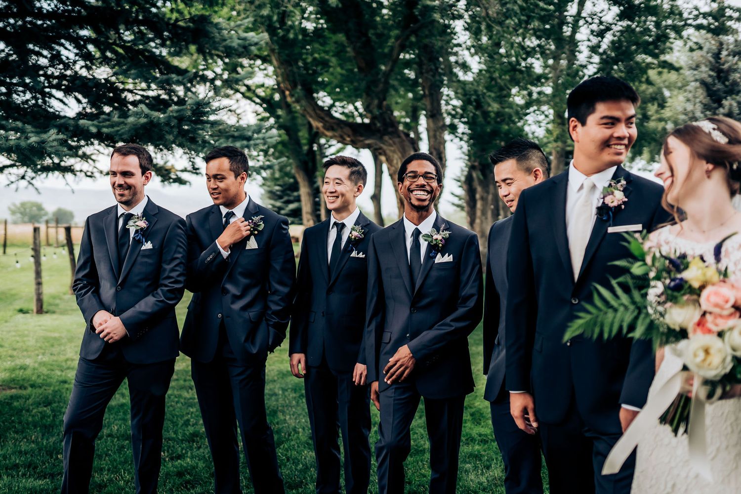 Wedding party in navy suits sharing a lighthearted moment outdoors.