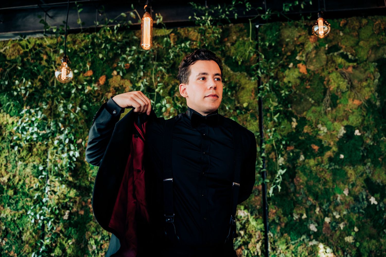 A formal event photo at night with greenery and string lights creating an elegant ambiance.