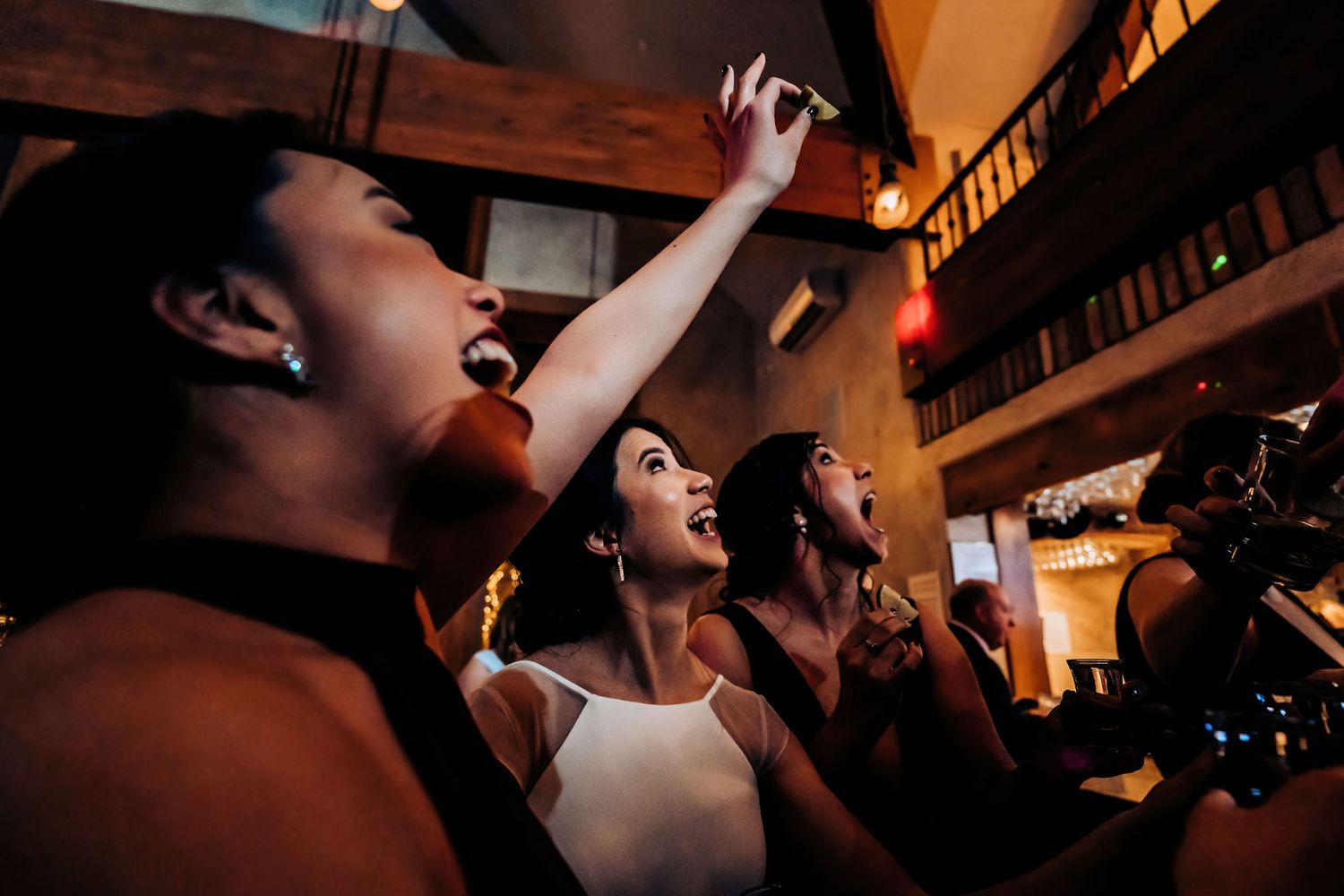 Guests passionately sing along during a wedding reception celebration.