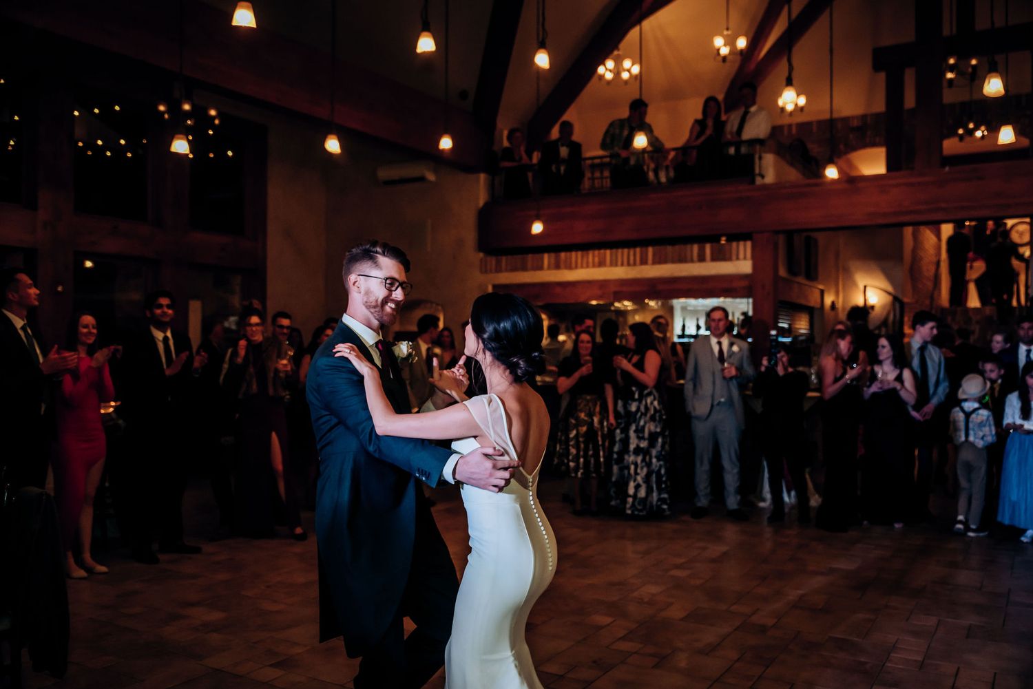 Couple sharing their first dance on a wooden dance floor during their wedding reception.