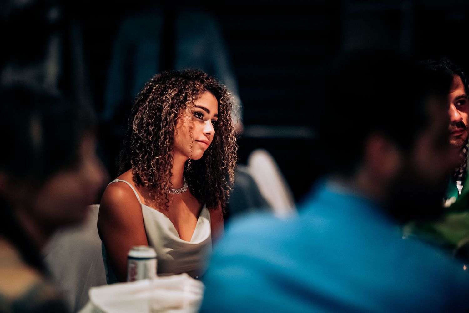 A guest in evening attire smiles during a formal dinner event.