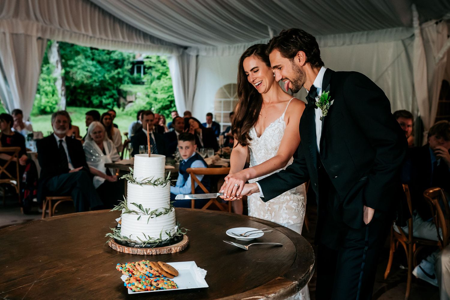 Newlyweds cut their three-tiered wedding cake together during their reception celebration.