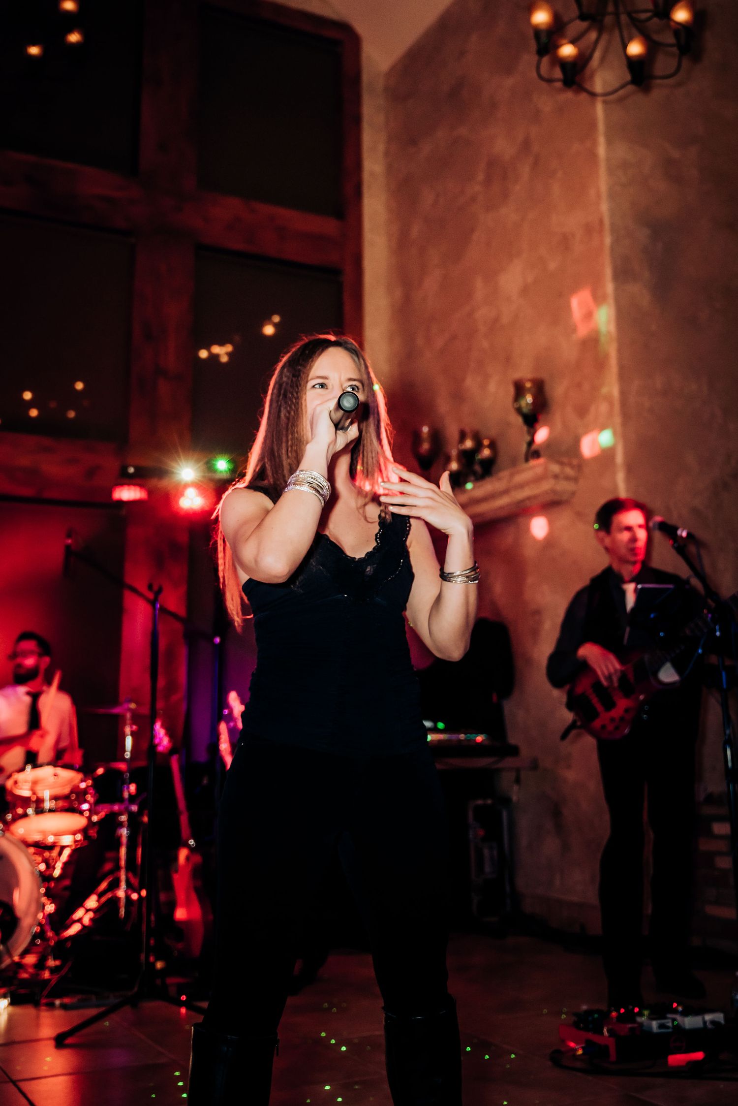 A live band performs on stage with a singer in black and musicians in moody red lighting.