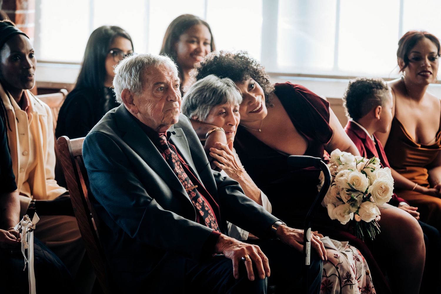 Wedding guests seated in rows watching emotional ceremony proceedings.