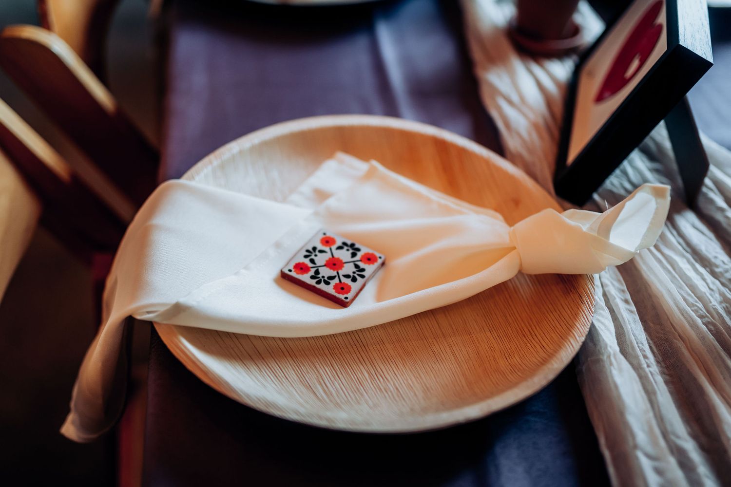 Close-up of place setting with decorative pin on white napkin.
