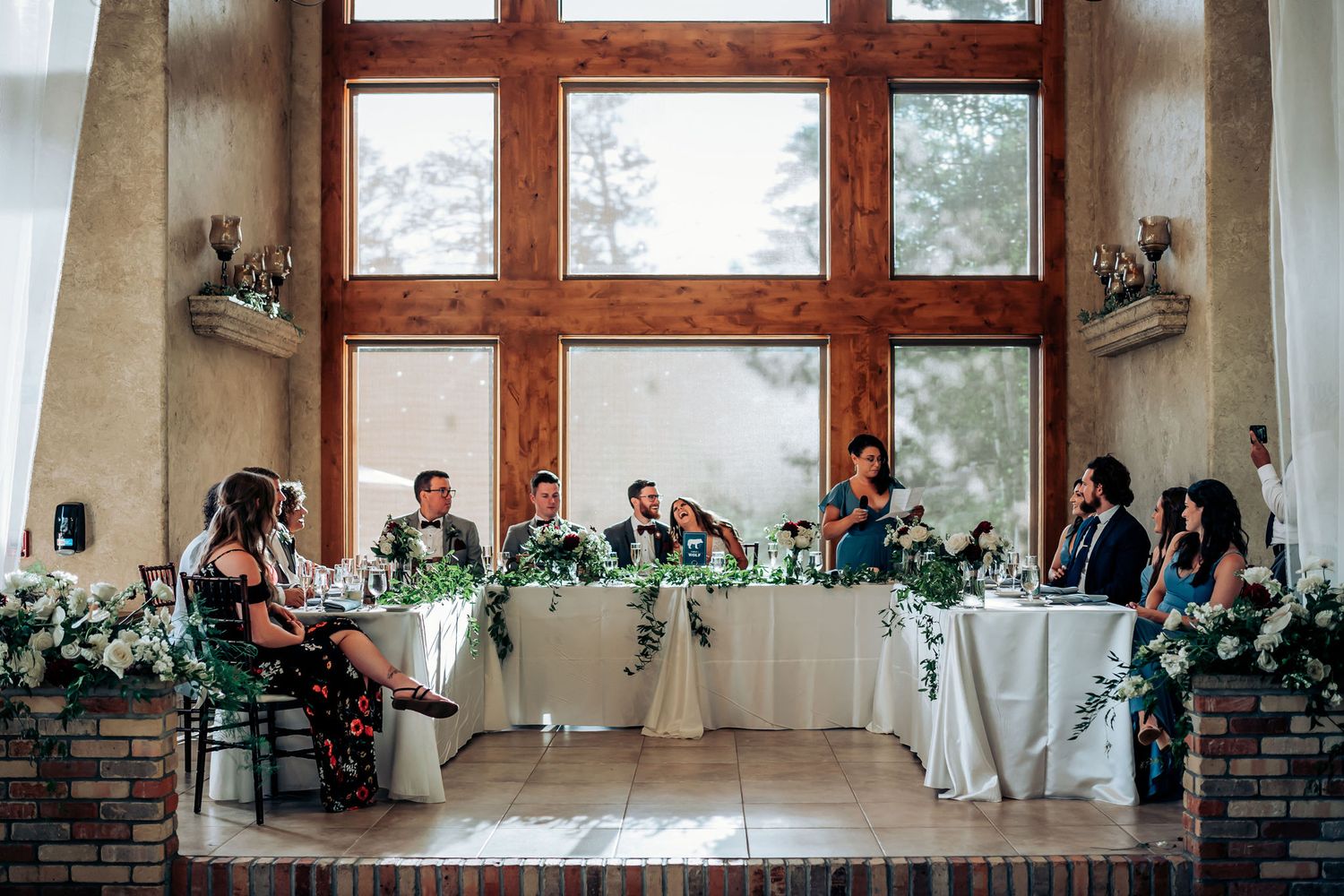 Wide shot of wedding reception setup with rustic wood beams and elegant white table decor.