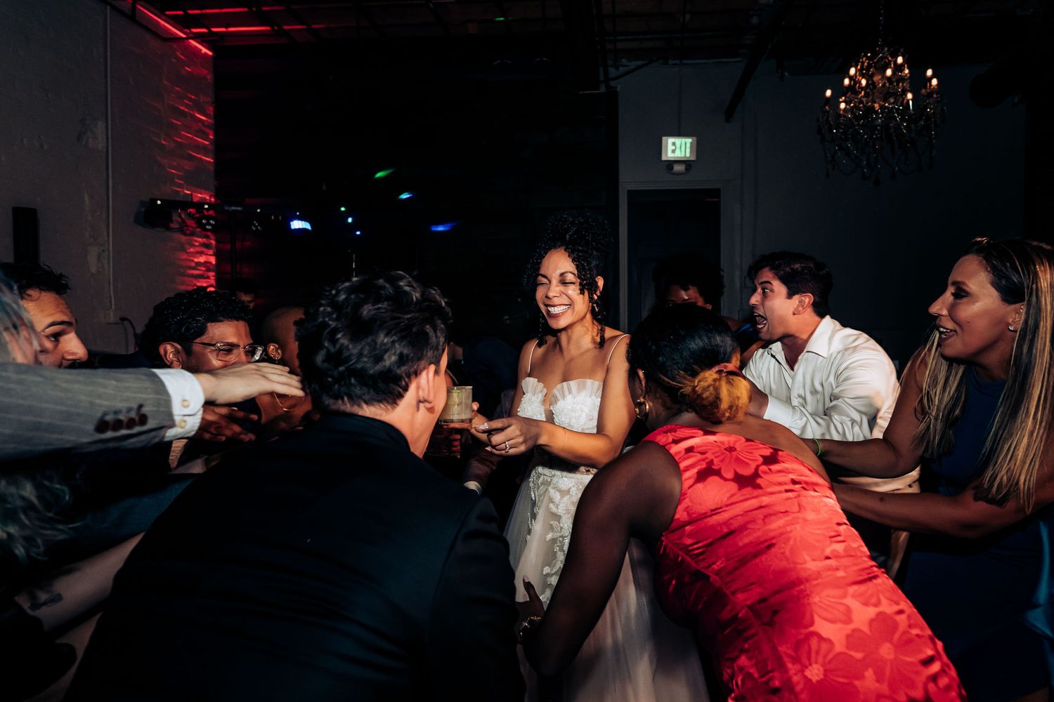 Wedding guests gathered around a dimly lit table enjoying intimate conversation at a reception celebration.