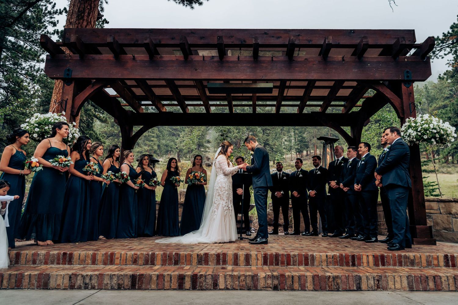 Wedding ceremony on brick platform with bridal party in navy and black forming symmetrical lines.