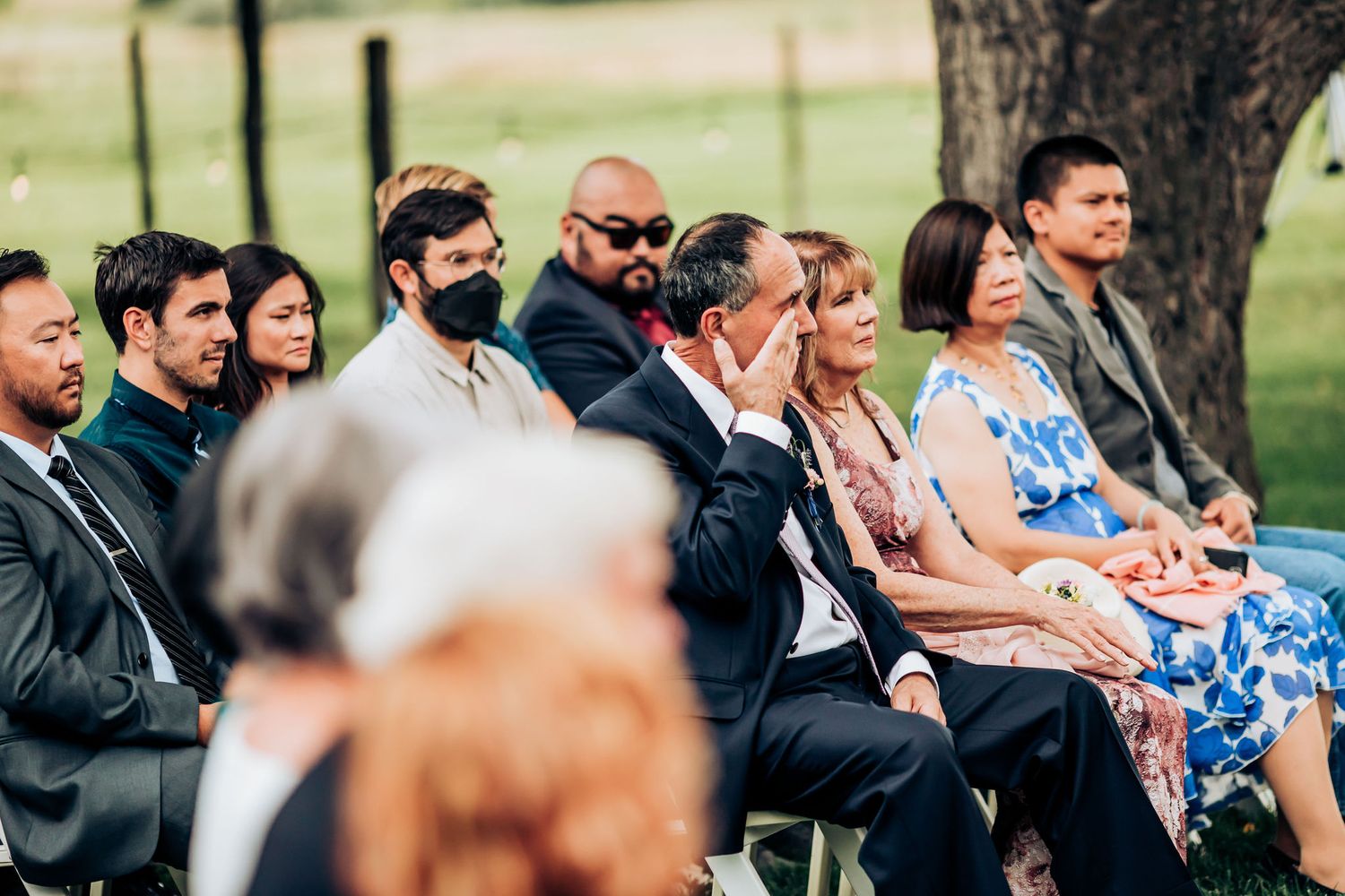 Wedding guests seated in formal attire watching the outdoor ceremony.