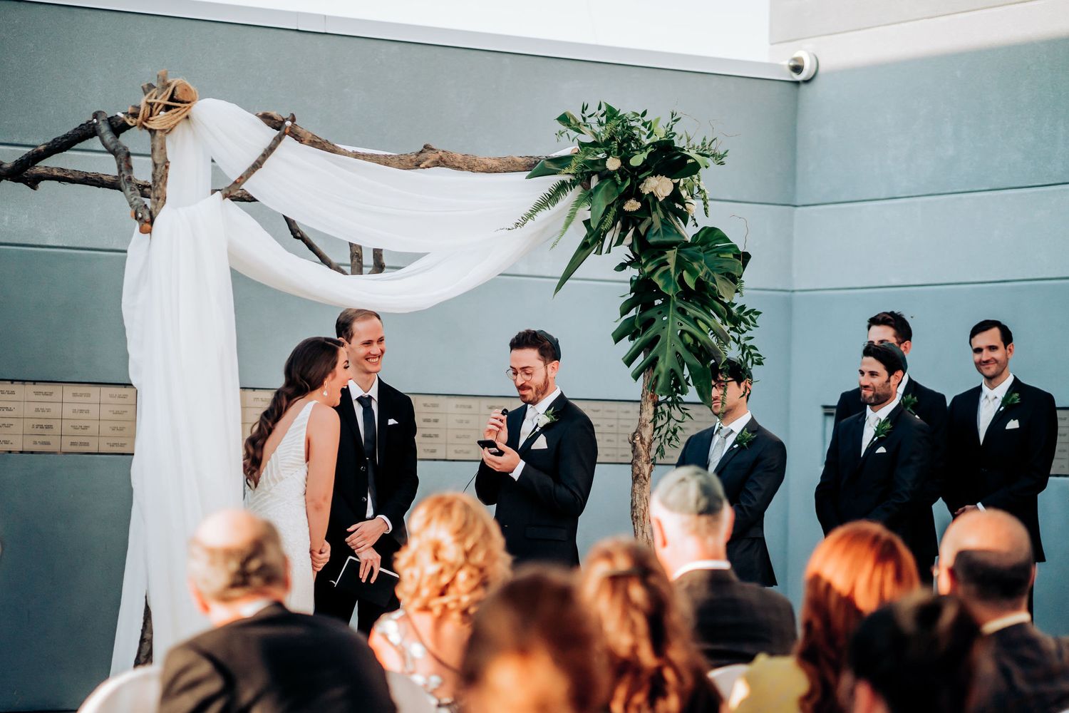 Wedding celebration under elegant white fabric arch with floral accents.