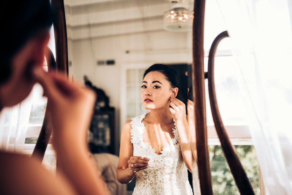 Final touches of wedding preparation captured in mirror reflection with natural lighting.