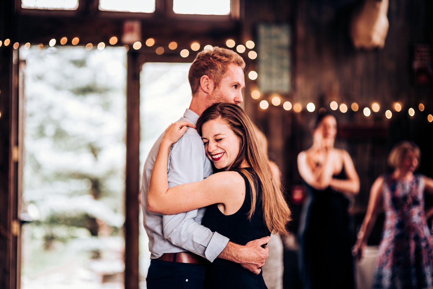 Couple sharing an intimate dance moment under twinkling lights at an indoor venue.