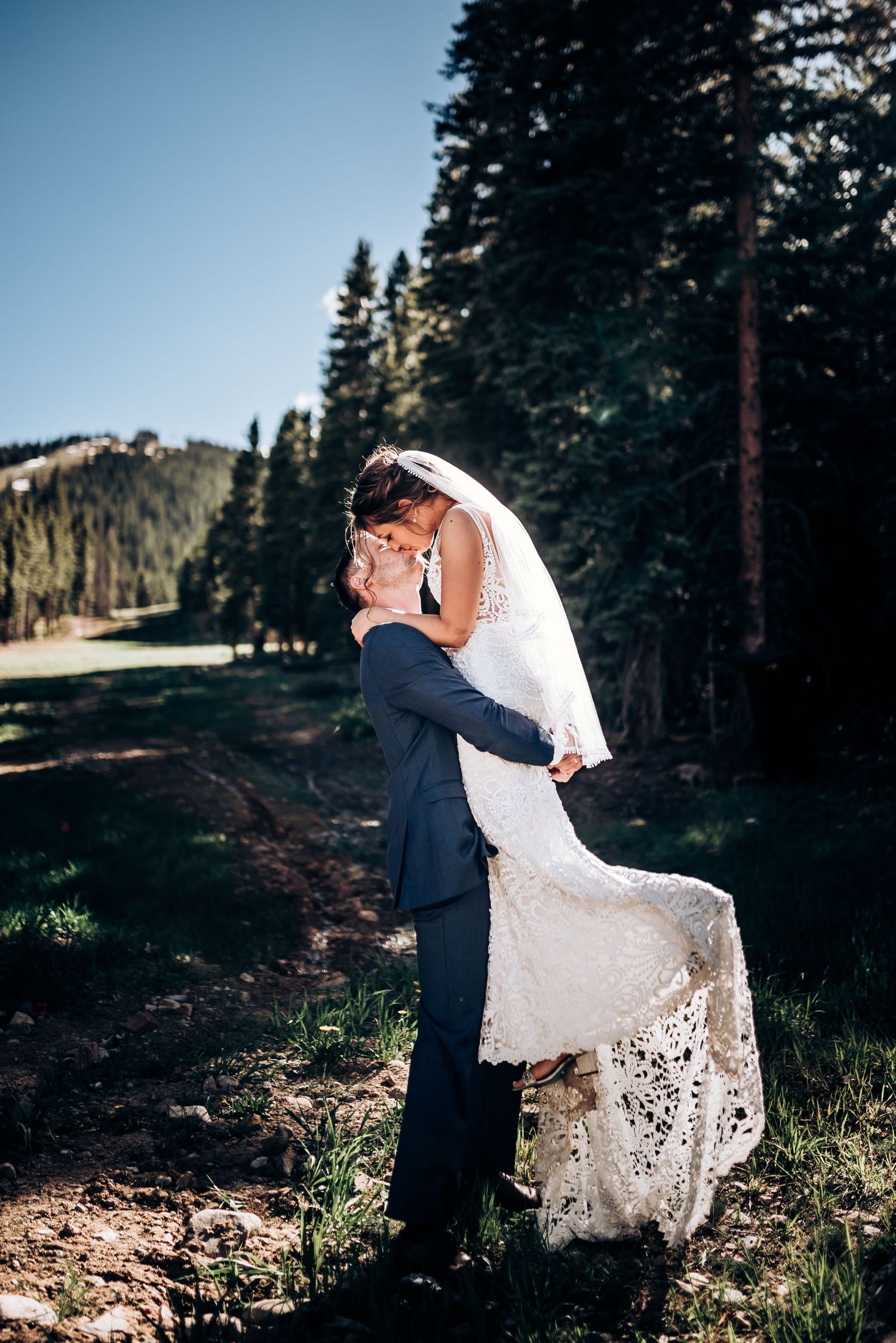A romantic lift pose during a mountain wedding photoshoot with forest backdrop.