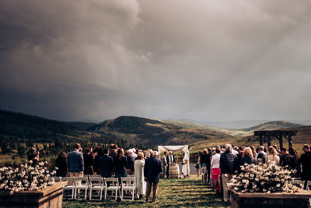 Mountain landscape backdrop for outdoor wedding ceremony with rows of white chairs.