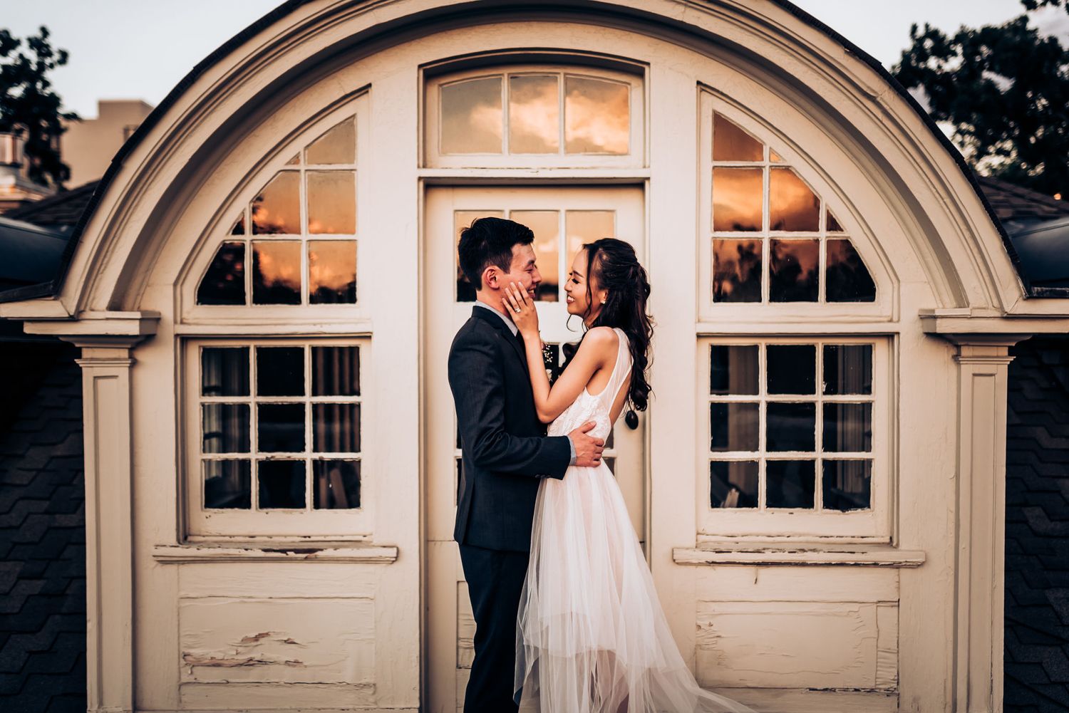 A couple embraces in front of an elegant arched doorway at their wedding.