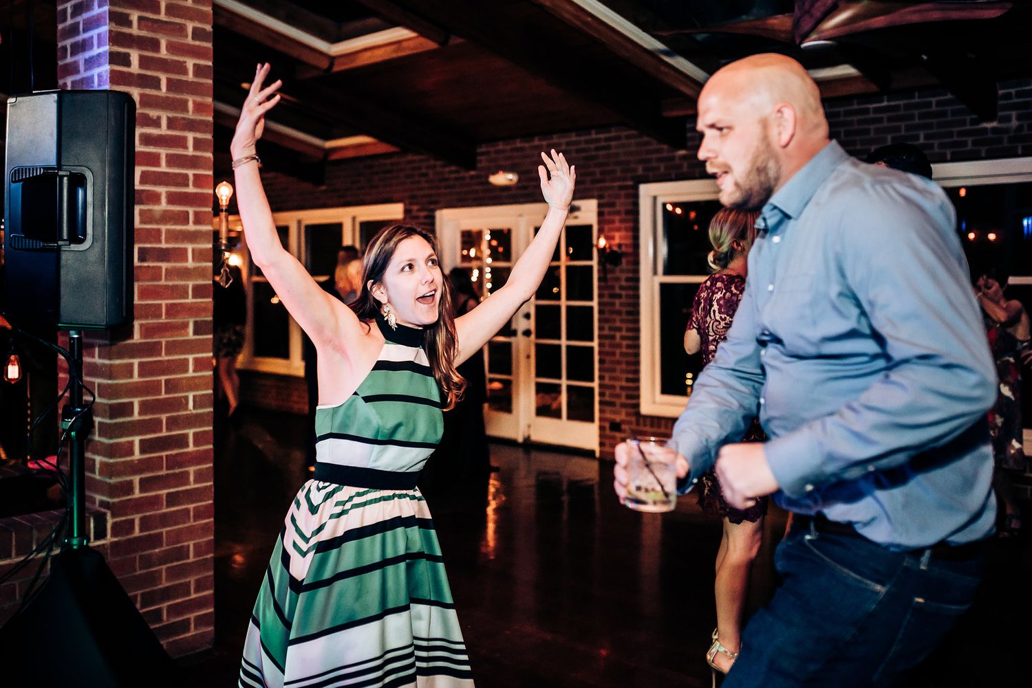 Guest dances enthusiastically at wedding reception while others enjoy the celebration.
