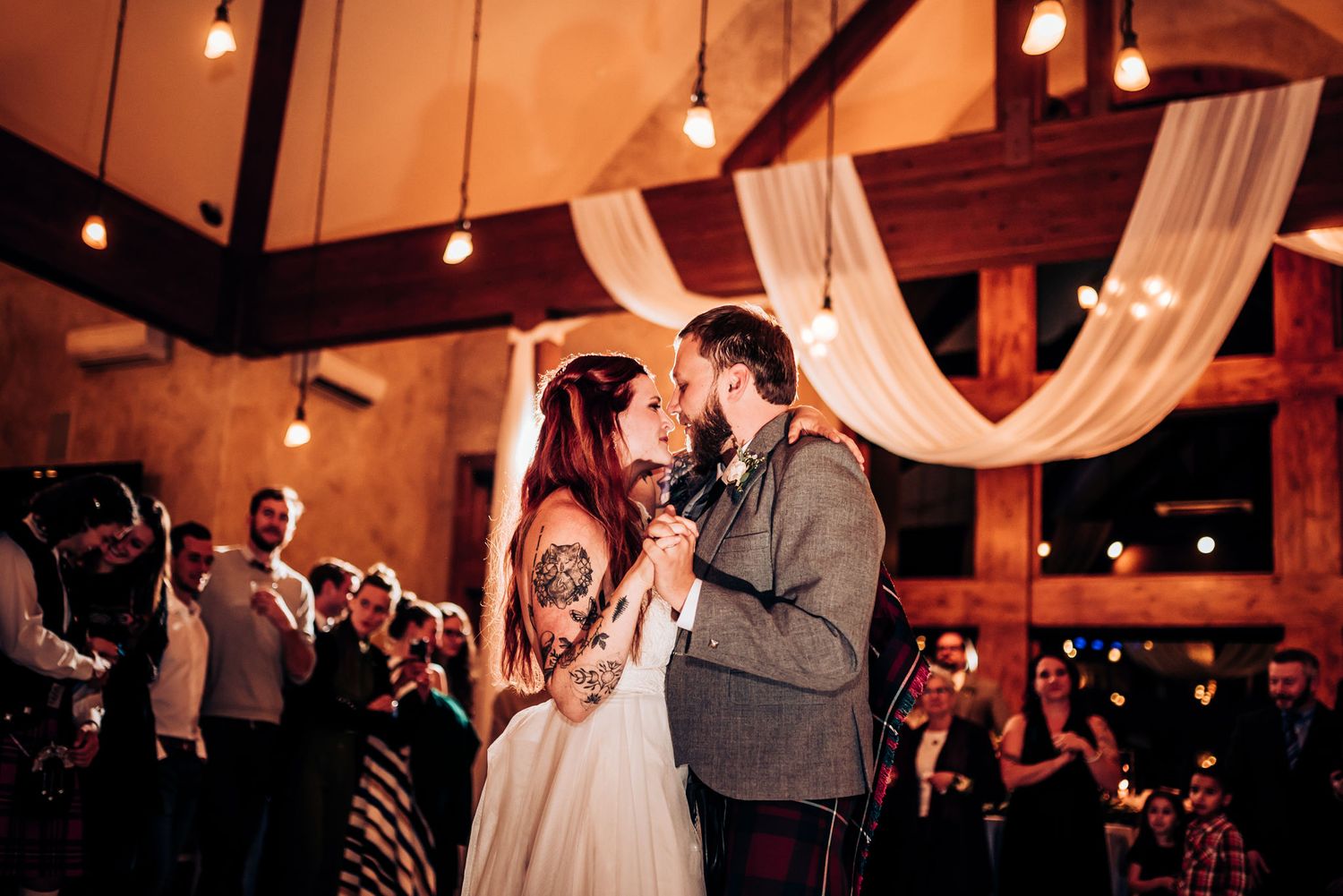 Romantic dance moment under draped fabric and warm lighting at wedding reception.