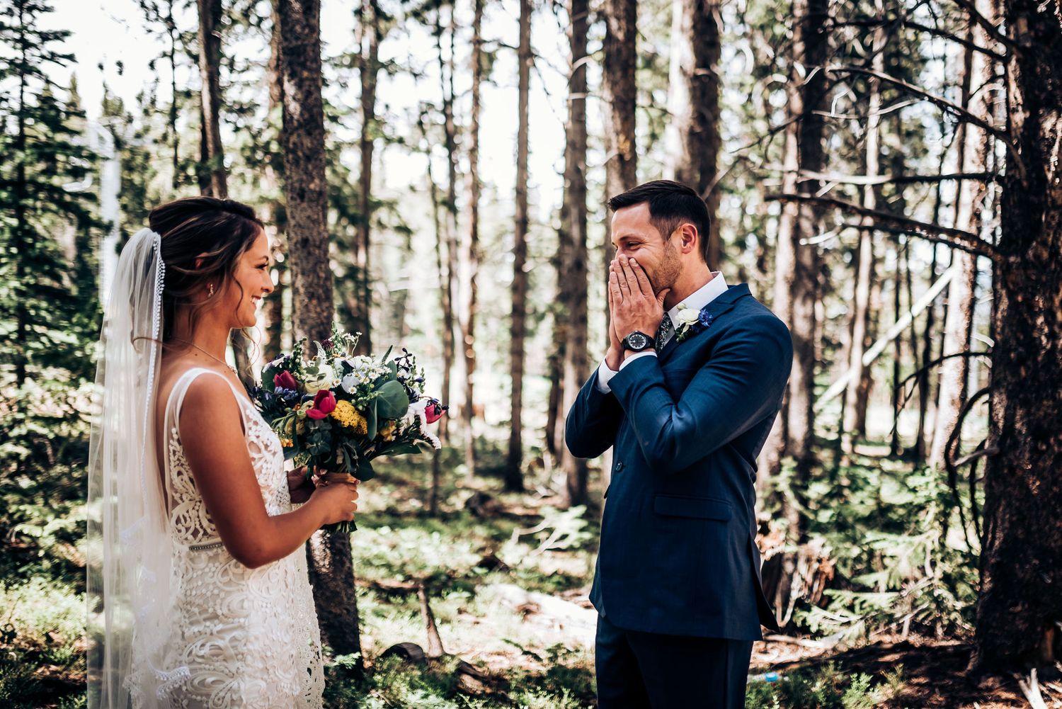 An emotional wedding ceremony moment captured between newlyweds in a wooded forest setting.