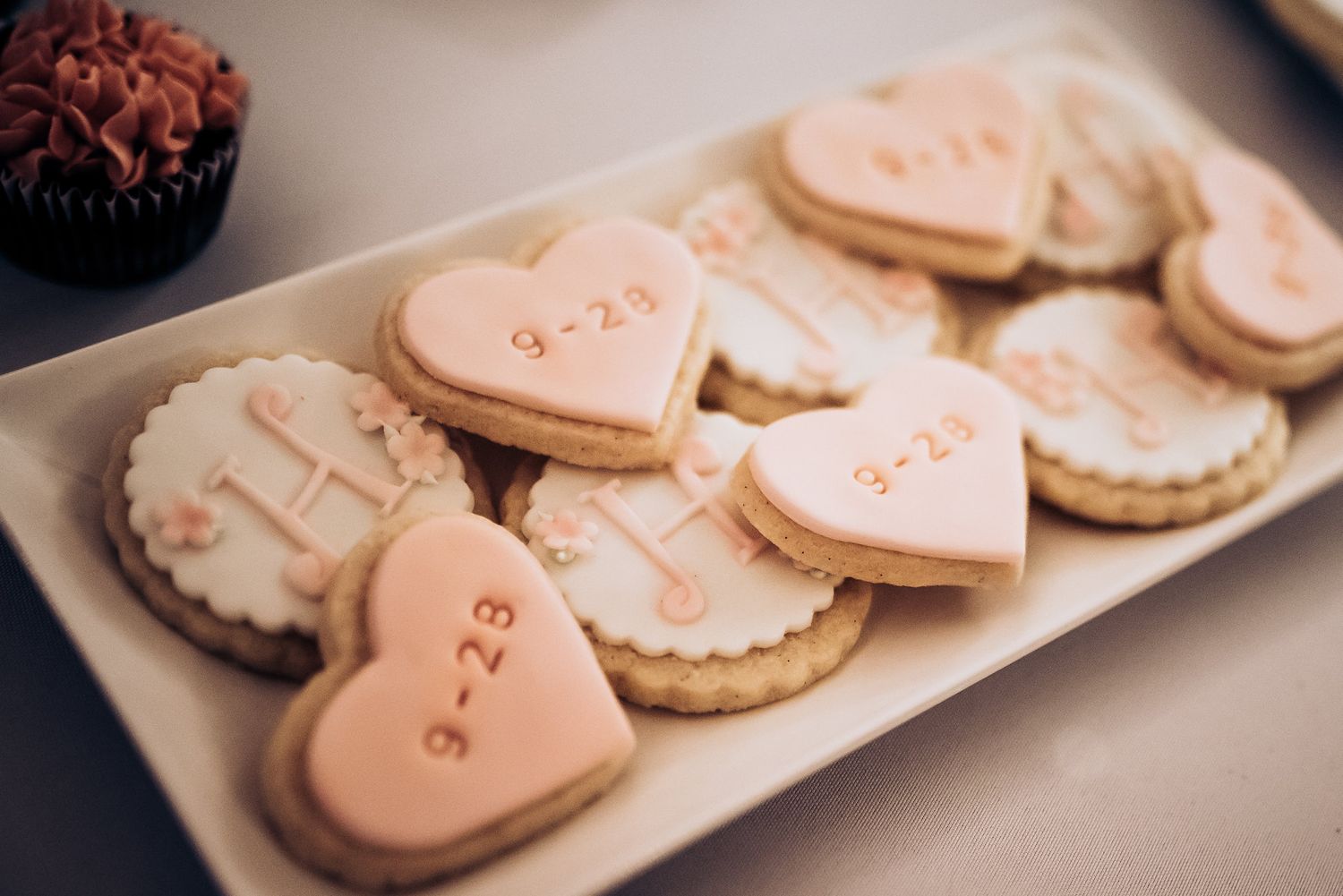 Heart-shaped pink cookies with personalized dates decorated for a wedding celebration.