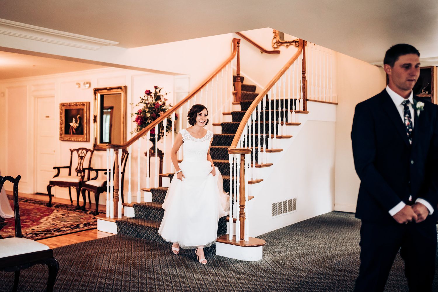A wedding scene in an elegant foyer with a decorated staircase and classic decor.